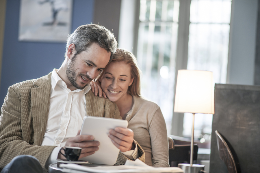 Couple sitting at their table looking at a tablet. 